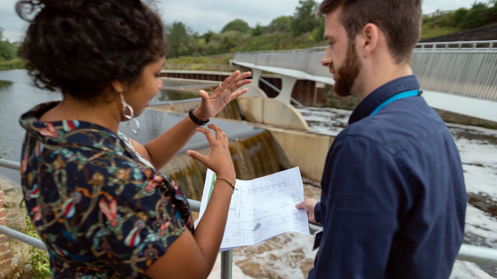 Civil engineers reviewing technical drawings beside an infrastructure project.